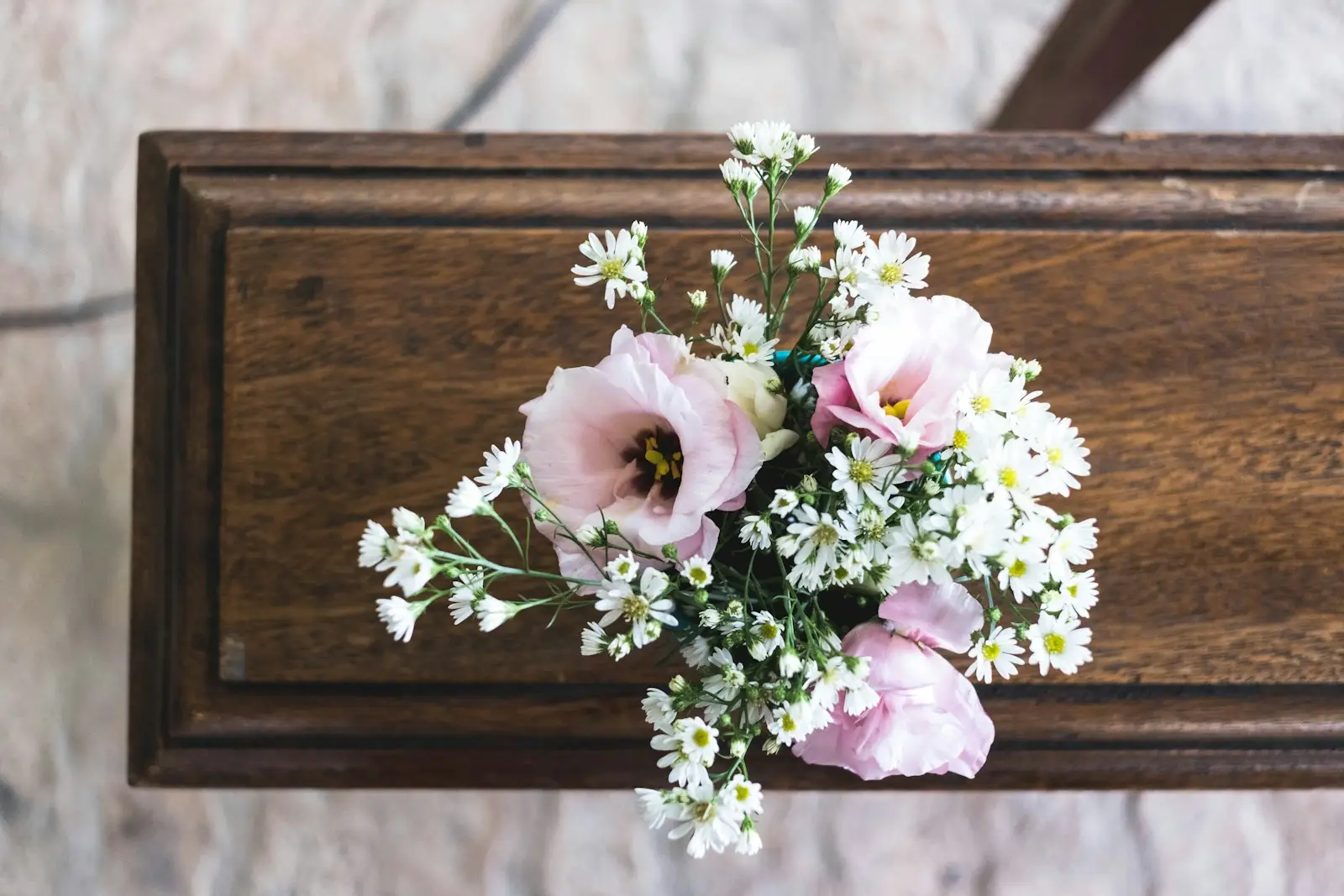 Bouquet of soft pink and white flowers placed on top of a wooden casket