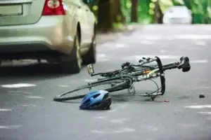 Bicycle lying on the road with a blue helmet beside it after a collision with a car.